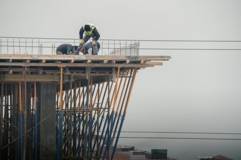 Foreign construction workers holding SKKP CIDB Malaysia certificates on a construction site